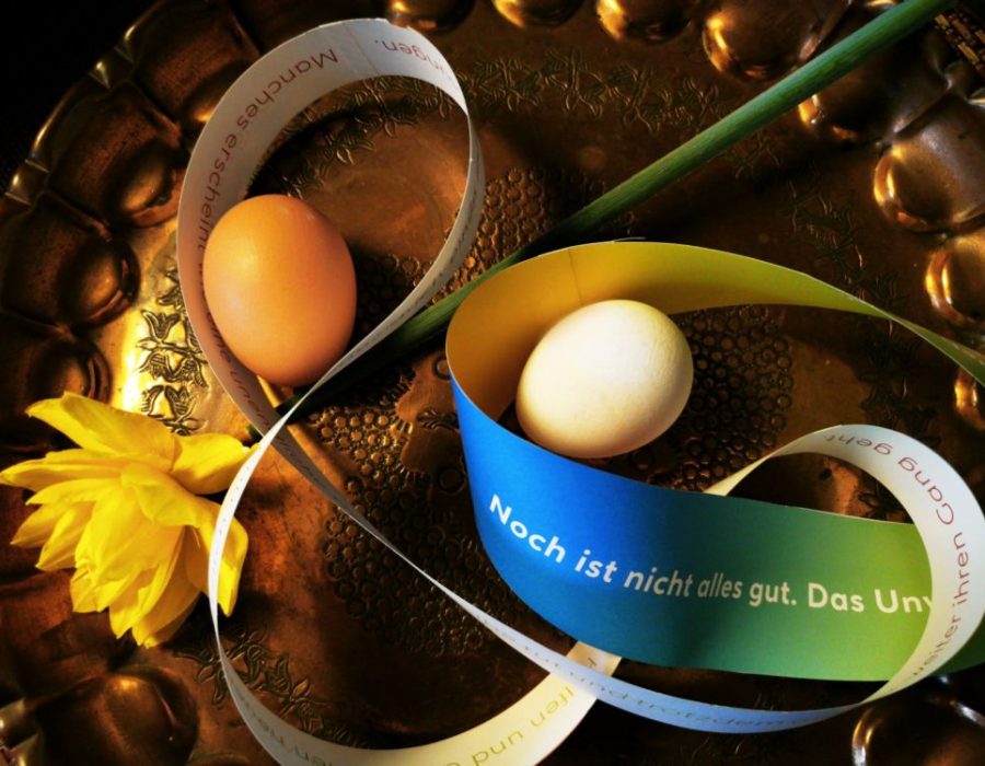 König Konzept versendet jedes Jahr Ostergrüße an Kunden und Freunde. 2023 wurde das Material für ein Möbiusband mitgeliefert. Auf diesem Foto sieht man das erstellte Möbiusband aus Papier dekoriert mit zwei Eiern und einer Osterglocke.
